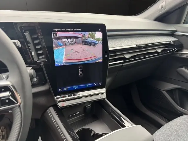 Vue intérieure du tableau de bord du Renault Austral bleu, avec écran tactile central affichant la caméra de recul.