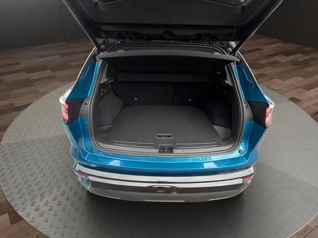 Vue arrière du Renault Austral bleu avec hayon motorisé ouvert dévoilant le coffre spacieux et l'intérieur sombre.