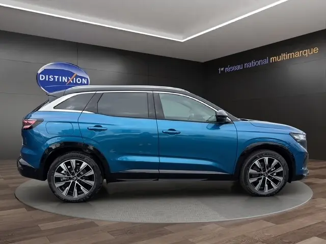Profil droit du Renault Austral 2026 bleu bi-ton avec toit noir et jantes alliage distinctives en showroom.