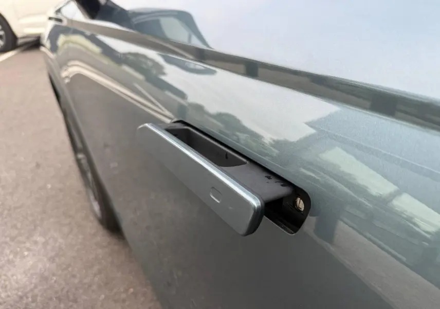 Poignée de porte rétractable côté gauche d'une JAECOO J7 Olive Grey Métal avec reflet du toit Carbon Crys Black.