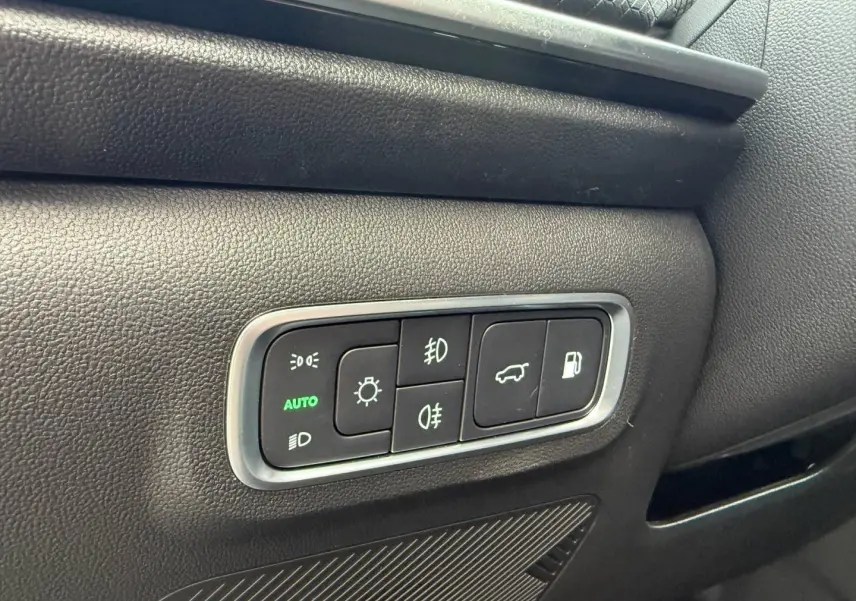Détail des commandes d’éclairage et d’ouverture du coffre sur la porte côté conducteur d’un JAECOO J7 olive gris métal.