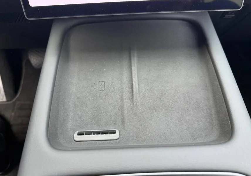 Gros plan sur le plateau de recharge sans fil noir mat au centre de la console intérieure du JAECOO J7 2026.