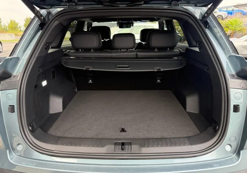 Coffre ouvert vu de l'arrière d'un JAECOO J7 olive grey métal avec intérieur noir et cache-bagages.