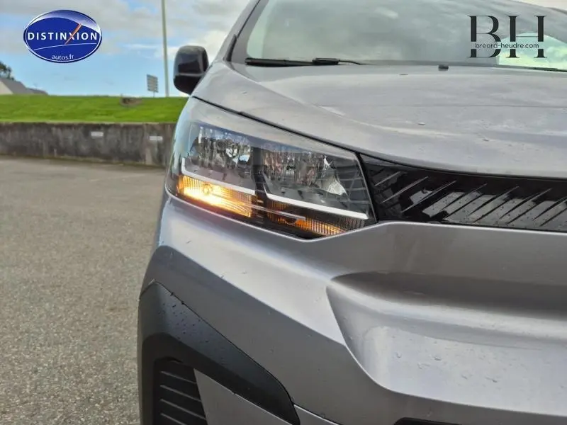 Gros plan sur le phare avant gauche allumé d'un Citroën Jumpy Fourgon XL gris acier métal, avec calandre noire brillante.
