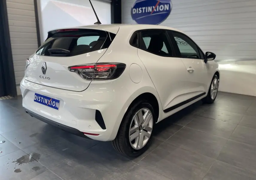Vue 3/4 arrière droite d'une Renault Clio blanche avec feux LED et jantes alliage dans un showroom.