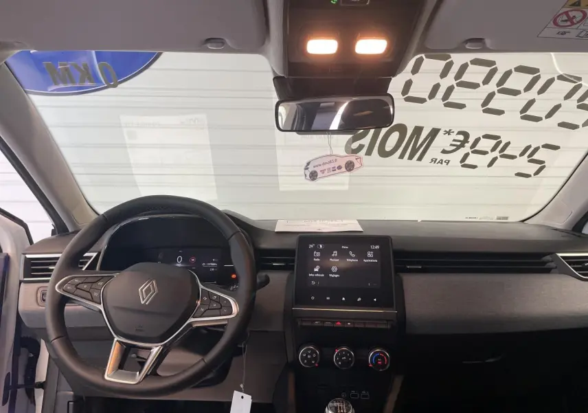 Vue intérieure frontale du tableau de bord de la Renault Clio 2025 avec volant multifonction et écran tactile central.
