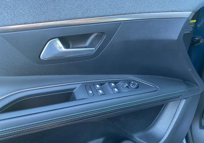 Vue rapprochée de la porte avant gauche du Peugeot 3008 Bleu Celebes, montrant les commandes des vitres et le décor avec surpiqûres bleues.