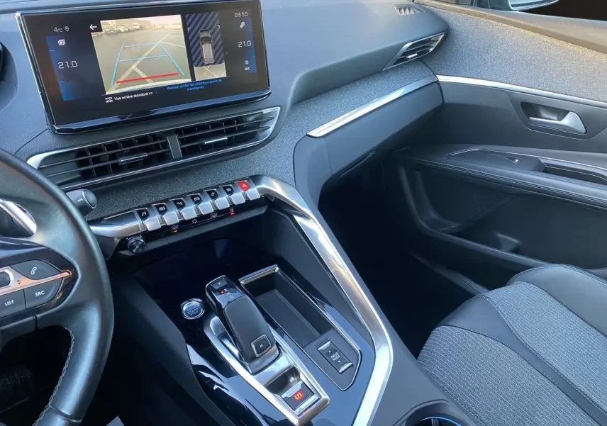 Vue intérieure côté passager du Peugeot 3008 Bleu Celebes 2021, avec console centrale moderne et écran tactile affichant la caméra de recul.