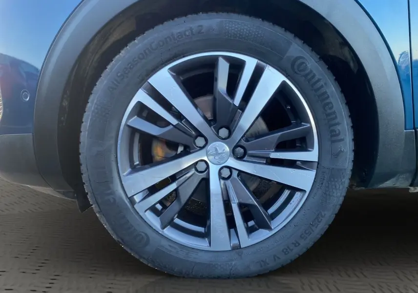 Gros plan sur la roue avant droite du Peugeot 3008 Bleu Célèbes, jante alliage à design moderne.
