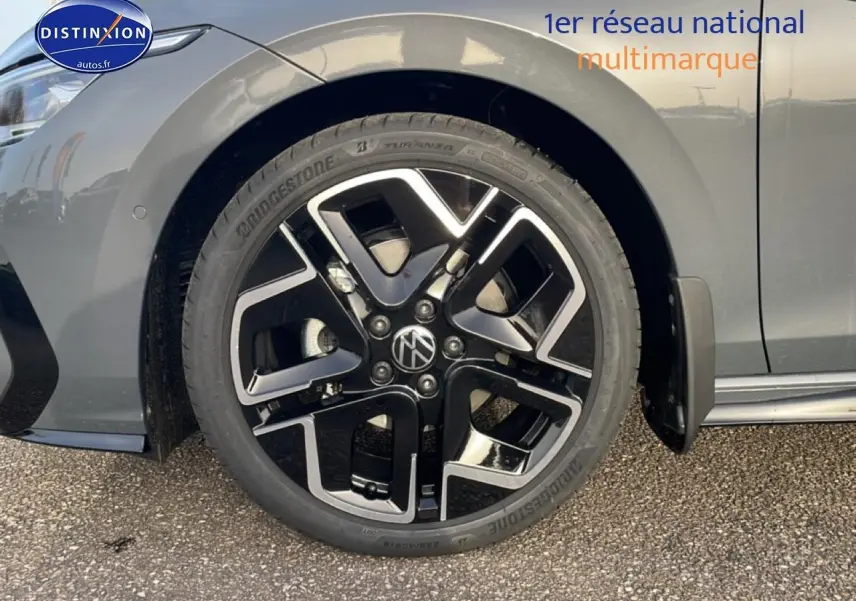 Gros plan sur la roue avant gauche d'une Volkswagen Golf gris métallisé avec jante alu noire et argent.