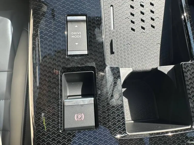 Gros plan sur la console centrale noire brillante du Citroën C5 Aircross 2026 avec bouton Drive Mode et frein à main électrique.