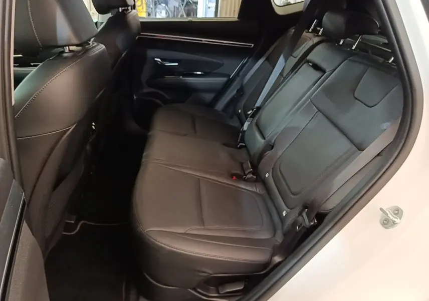 Vue intérieure côté droit des sièges arrière noirs en cuir du Hyundai Tucson blanc 2022, avec ceinture de sécurité visible.