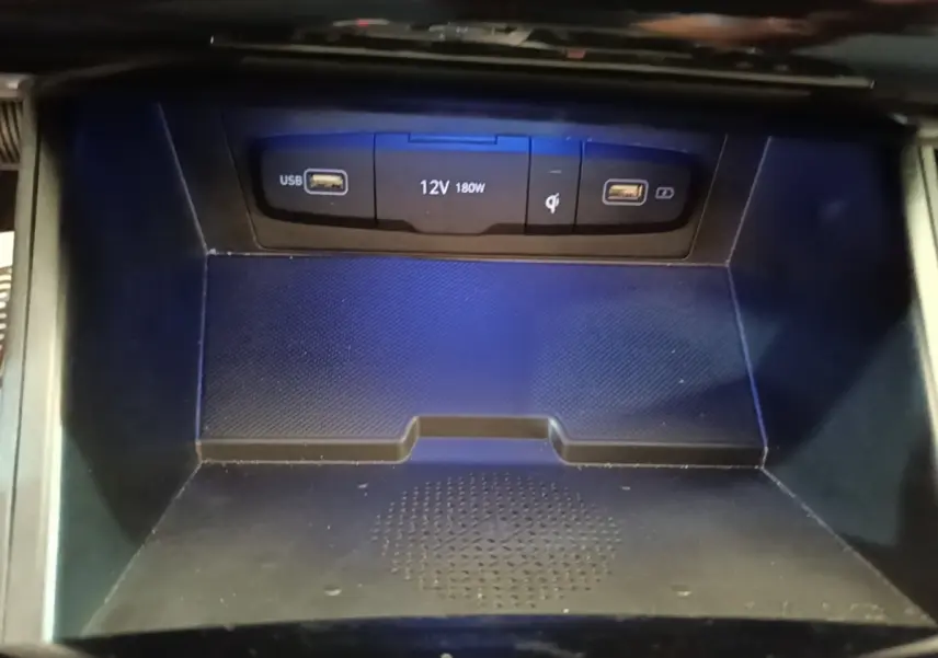 Gros plan sur la zone de recharge à induction noire avec ports USB et prise 12V dans une Hyundai Tucson 1.6 Hybrid 230 Executive.