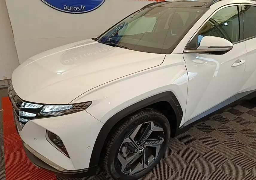 Vue 3/4 avant droit du Hyundai Tucson blanc avec phares LED et jantes alliage distinctives.