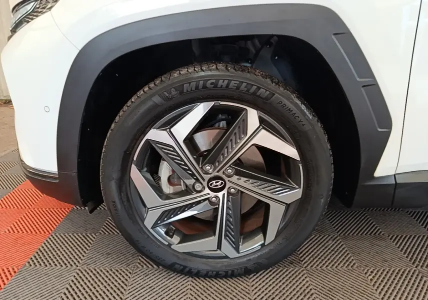 Gros plan sur la roue avant gauche du Hyundai Tucson blanc 2022 avec jante alliage au design moderne.