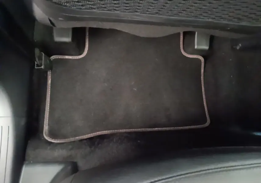 Plancher côté passager avec tapis noir bordé de surpiqûres marron dans un Hyundai Tucson blanc 2022.