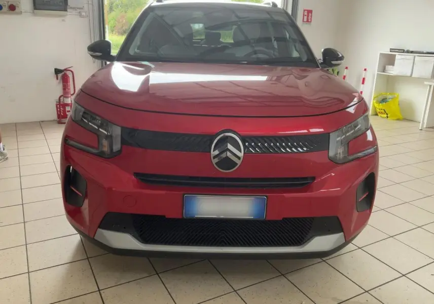 Vue avant d'une Citroën C3 ë-113 Berline Max rouge métal foncé, avec calandre noire et logo Citroën central.