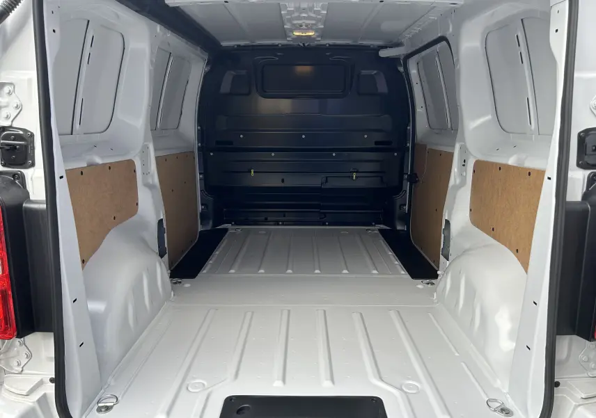 Intérieur du fourgon Citroën Jumpy blanc vu de l’arrière, montrant l’espace de chargement vide avec panneaux latéraux en bois.