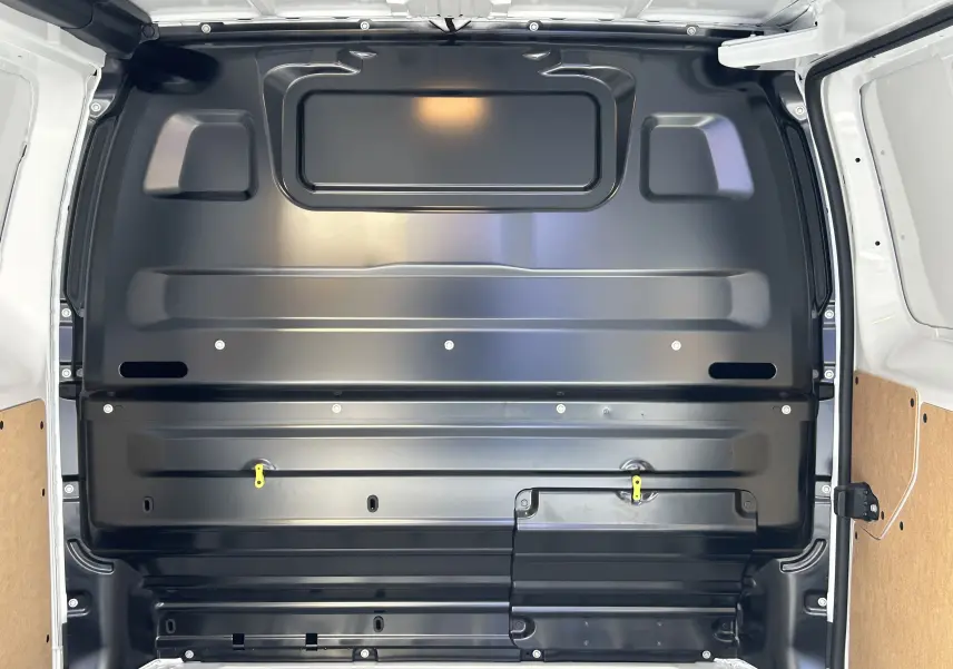 Vue intérieure arrière du fourgon blanc Citroën Jumpy 2025, montrant la cloison métallique noire séparant la cabine et la zone de chargement.