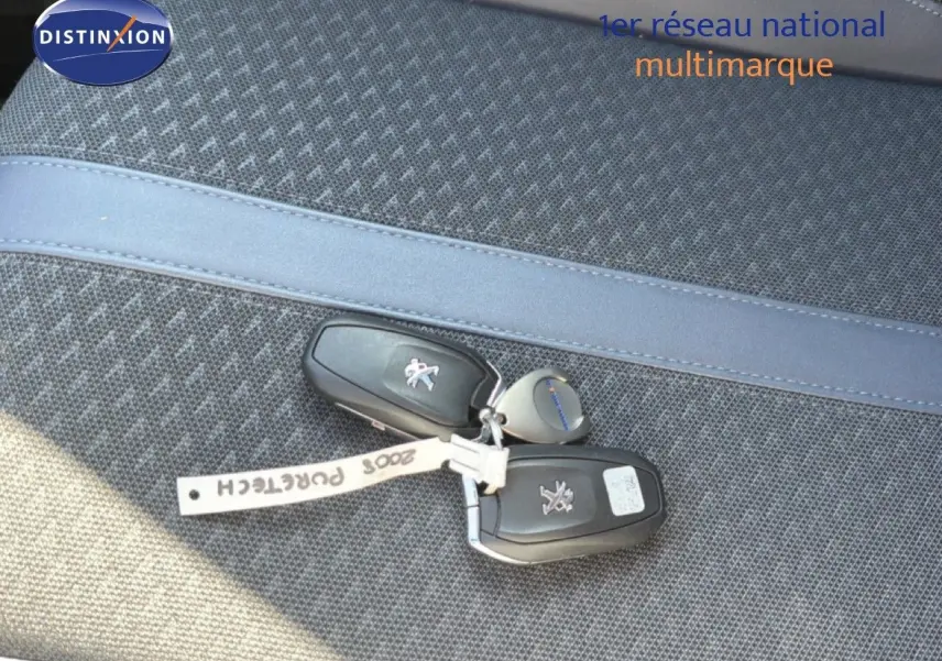 Je vois que l'image montre uniquement des clés de voiture posées sur un siège, sans vue du véhicule lui-même. Voici une description alt adaptée :

Clés de Peugeot 2008 posées sur un siège en tissu gris, sans vue du véhicule