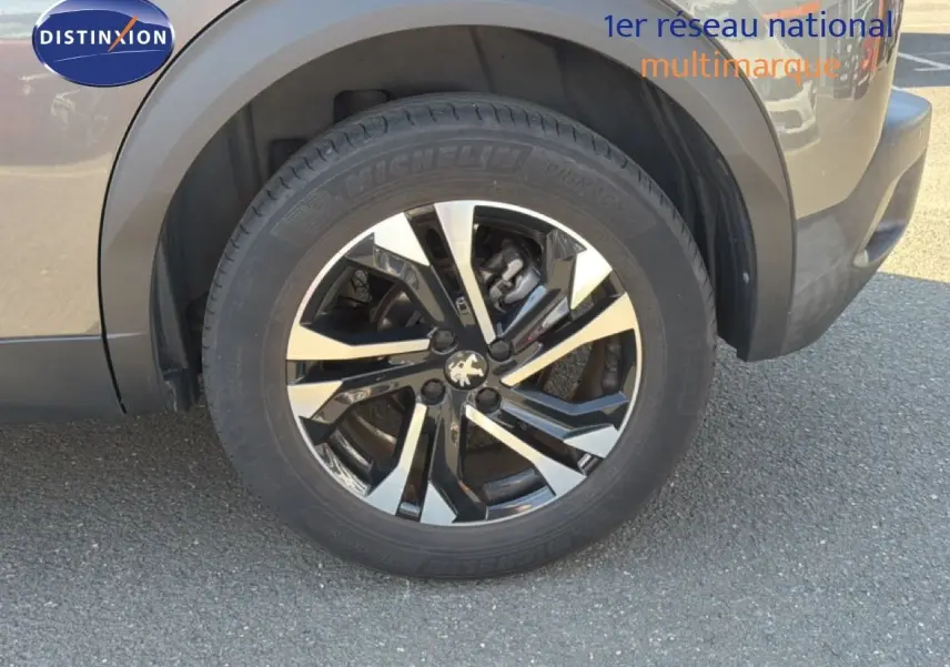 Gros plan sur la roue avant gauche avec jante alliage bicolore et carrosserie gris platinium du Peugeot 2008 2020.