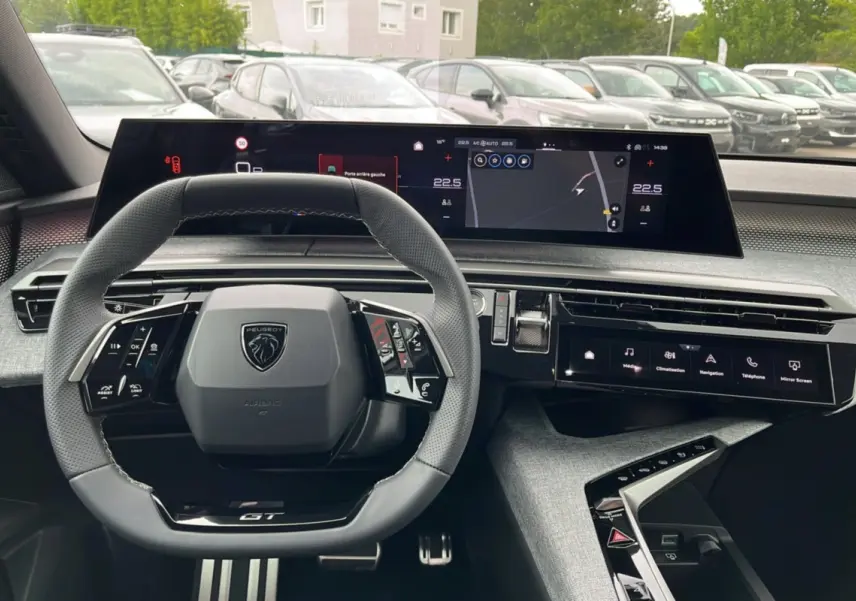 Vue intérieure du tableau de bord du Peugeot 5008 Hybrid 145 GT 2025 avec volant cuir et écrans numériques larges.