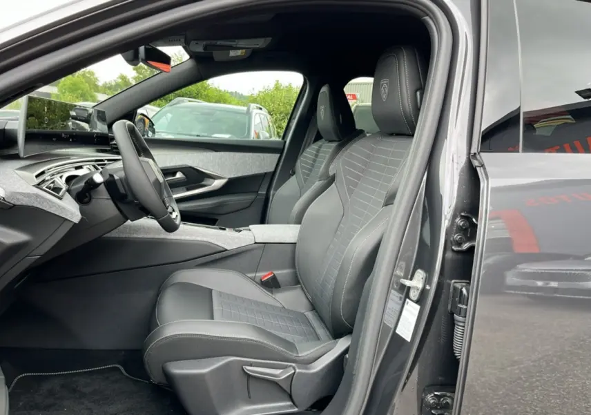 Vue intérieure côté conducteur du Peugeot 5008 gris titane avec sièges en cuir et tissu, volant multifonctions et tableau de bord moderne.