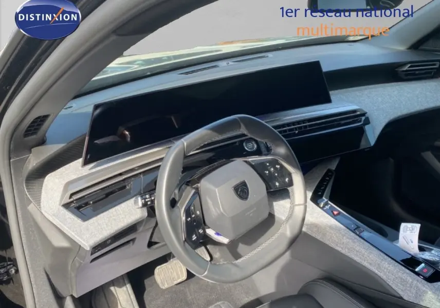 Vue intérieure côté conducteur du Peugeot 5008 Hybrid 2025, volant multifonction et tableau de bord moderne gris clair.
