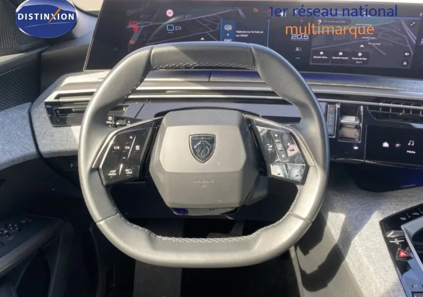 Vue rapprochée du volant cuir noir du Peugeot 5008 Hybrid 145ch 2025 avec tableau de bord numérique et commandes intégrées.
