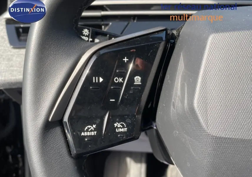 Gros plan sur les commandes au volant noir du Peugeot 5008 Hybrid 2025, avec boutons d’assistance et limitation de vitesse.