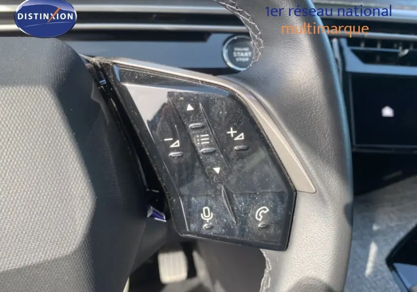 Gros plan sur les commandes au volant côté gauche du Peugeot 5008 Hybrid 2025 avec finition cuir noir et boutons multifonctions.