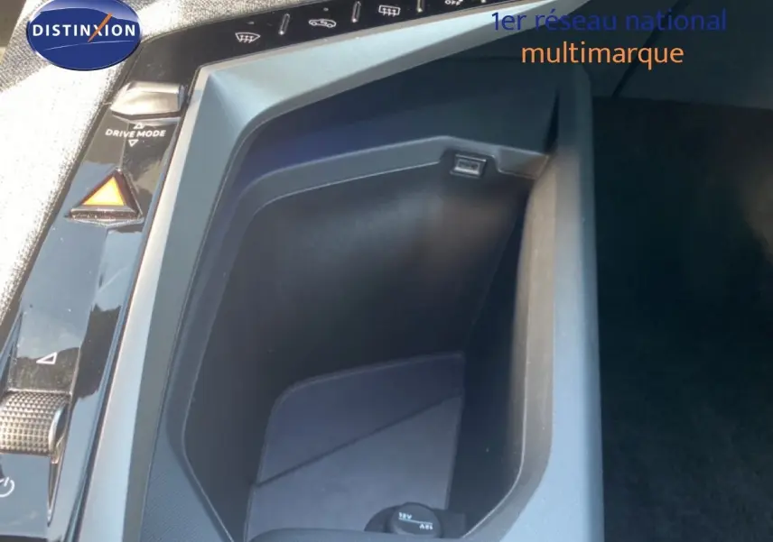 Gros plan sur la console centrale noire avec prise 12V et commandes de mode de conduite du Peugeot 5008 Hybrid 2025.