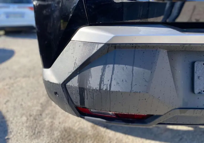 Gros plan sur le pare-chocs arrière droit noir métallisé du Peugeot 3008 1.2i Hybrid 2025 avec feu antibrouillard intégré.