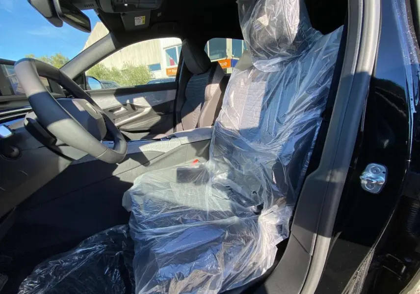 Intérieur du Peugeot 3008 noir 2025 vu côté conducteur, siège avant protégé par une housse plastique.