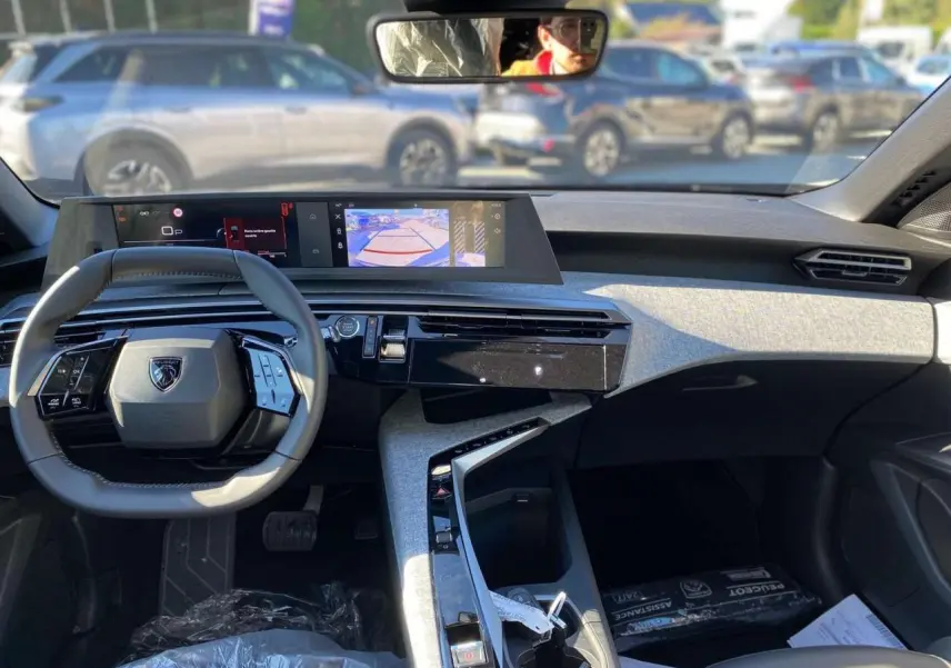 Vue intérieure avant du tableau de bord et volant gris du Peugeot 3008 noir 2025 avec écran tactile et console moderne.