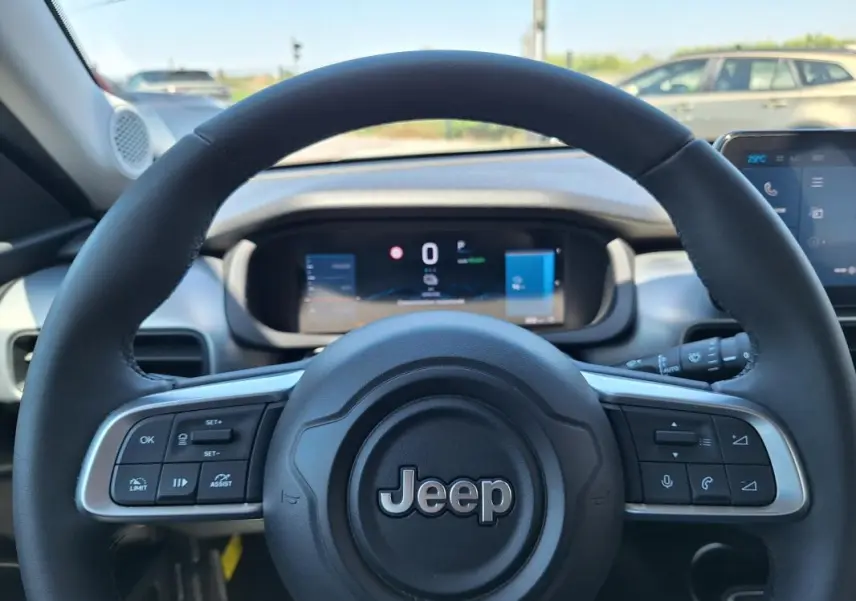 Vue rapprochée du volant Jeep Avenger électrique 2025, avec commandes intégrées et tableau de bord numérique visible.