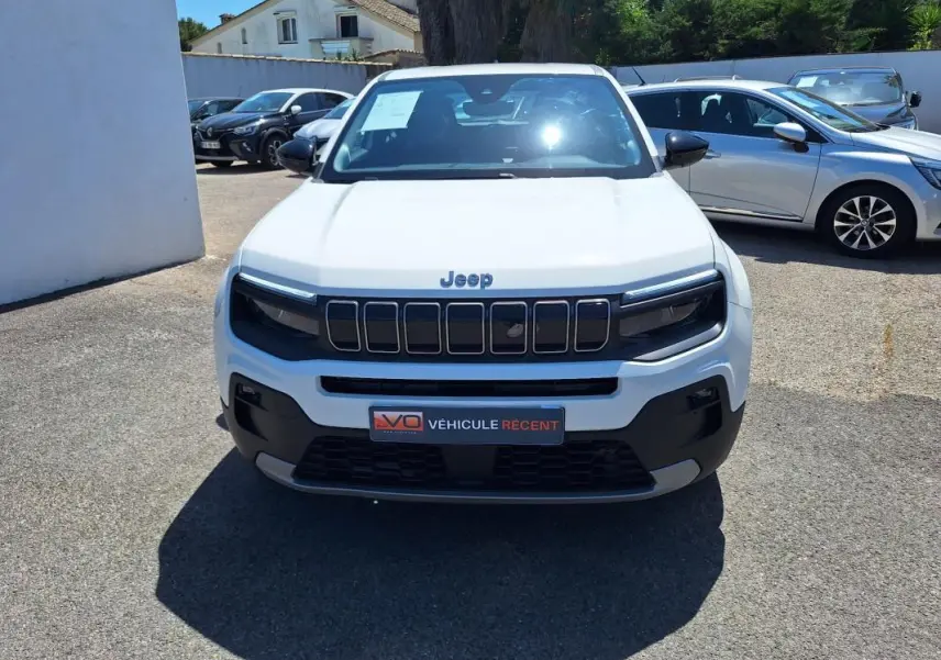 Vue avant d'un Jeep Avenger électrique blanc 2025 avec calandre noire et phares LED distinctifs.