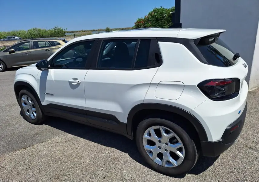 Jeep Avenger électrique blanc en vue 3/4 arrière droit, avec jantes alliage 17 pouces et vitres teintées.