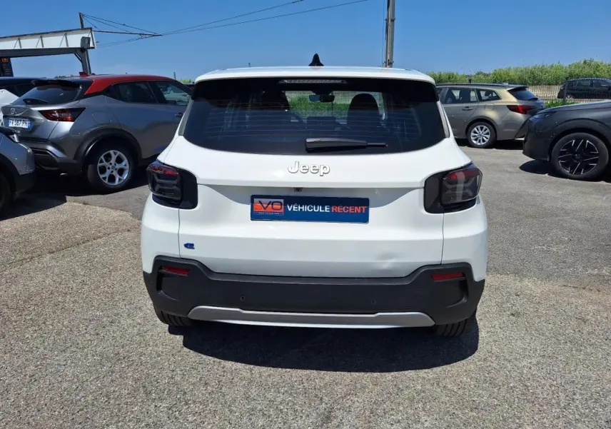 Vue arrière d'une Jeep Avenger électrique blanche 2025 avec feux arrière fumés et pare-chocs noir contrastant.