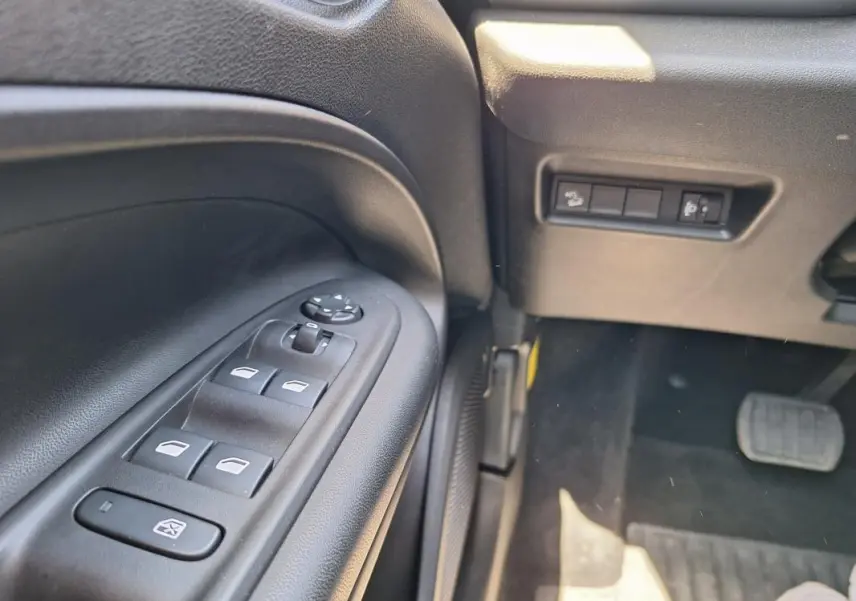 Vue rapprochée du panneau de commandes des vitres électriques côté gauche intérieur du Jeep Avenger blanc électrique 2025.
