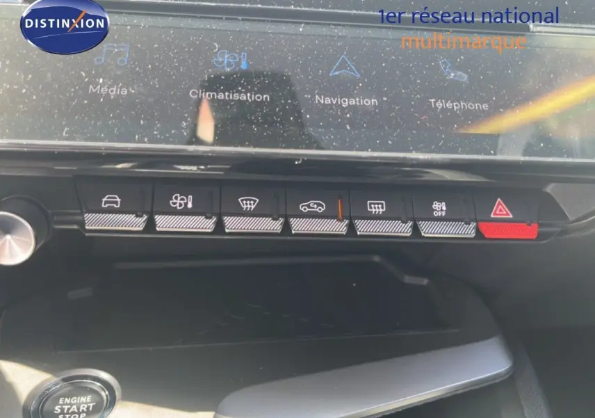 Vue rapprochée du tableau de bord de la Peugeot 308 Hybrid 2025, avec commandes tactiles et bouton start/stop visible.