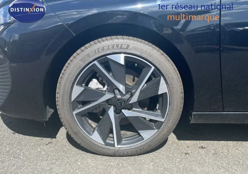 Gros plan sur la roue avant droite d’une Peugeot 308 noir métal avec jante alliage au design moderne.