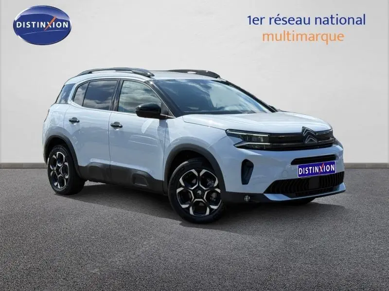 Vue 3/4 avant droit du Citroën C5 Aircross blanc Okénite avec jantes alu et barres de toit noires.