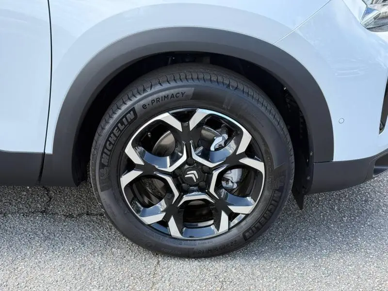 Gros plan sur la roue avant droite d’un Citroën C5 Aircross blanc Okénite avec jante alu noire et argentée.