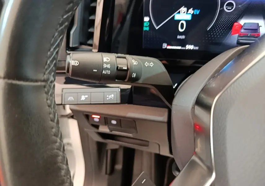 Gros plan sur le volant cuir et la commande des phares du tableau de bord du Renault Austral blanc hybride 2023.