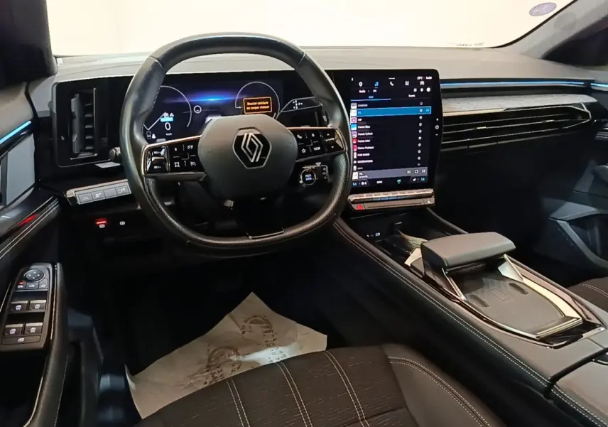 Vue intérieure du poste de conduite du Renault Austral blanc, avec volant cuir et grand écran tactile vertical.