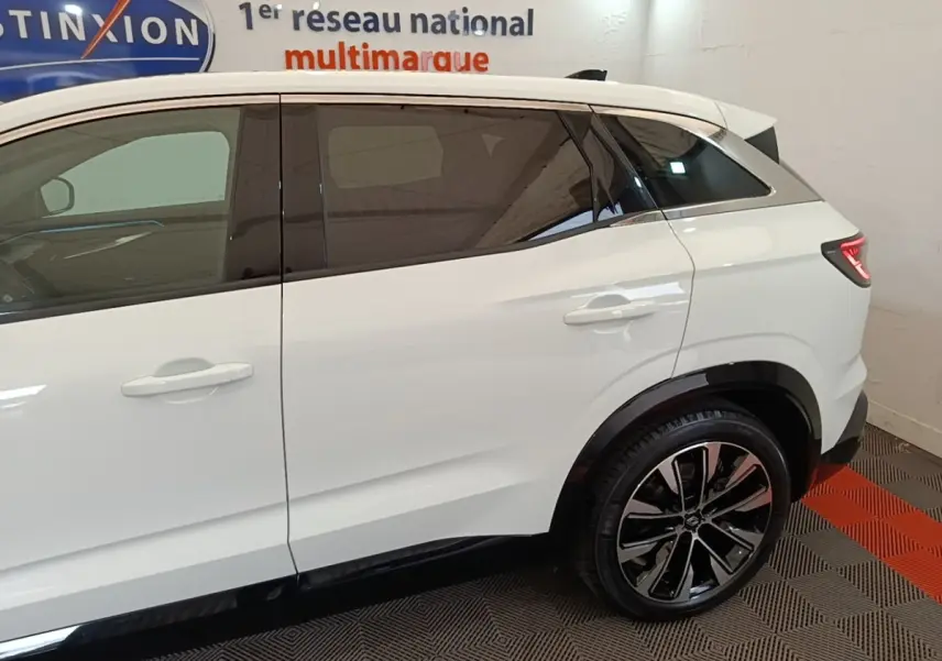 Vue côté droit arrière du Renault Austral blanc hybride 2023 avec jantes alliage et vitres teintées.