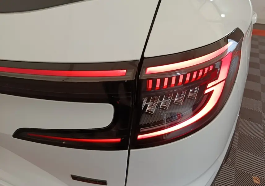Gros plan sur le feu arrière droit allumé du Renault Austral blanc, avec bande lumineuse rouge distinctive.