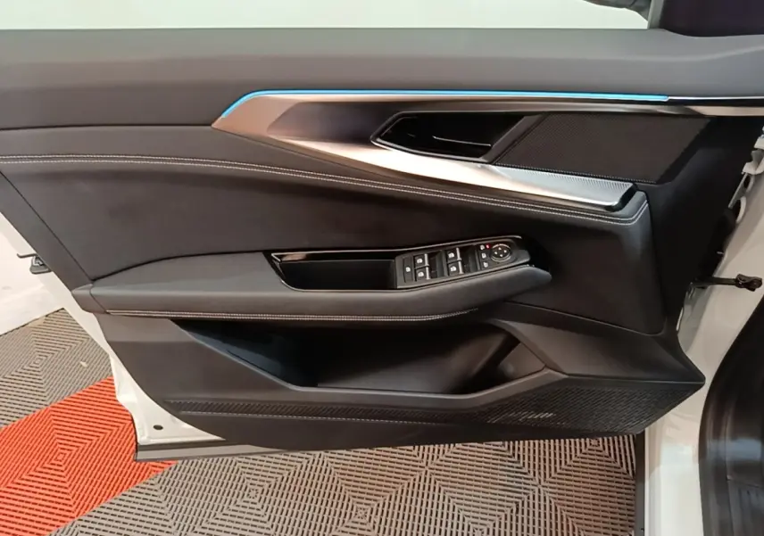 Vue latérale du panneau de porte avant gauche blanc du Renault Austral 2023 avec commandes électriques et bandeau lumineux bleu.