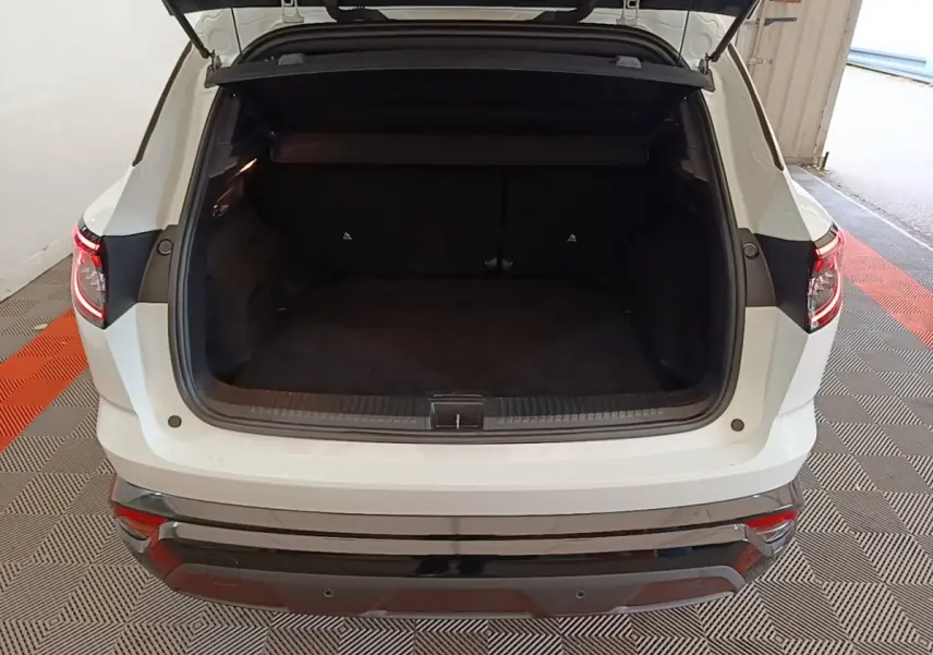 Coffre ouvert d’un Renault Austral blanc vu de l’arrière, montrant l’espace de chargement et les feux arrière LED allumés.
